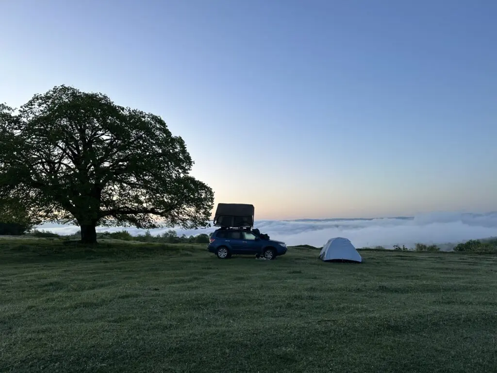 car with rooftop tent and ground tent camping above clouds