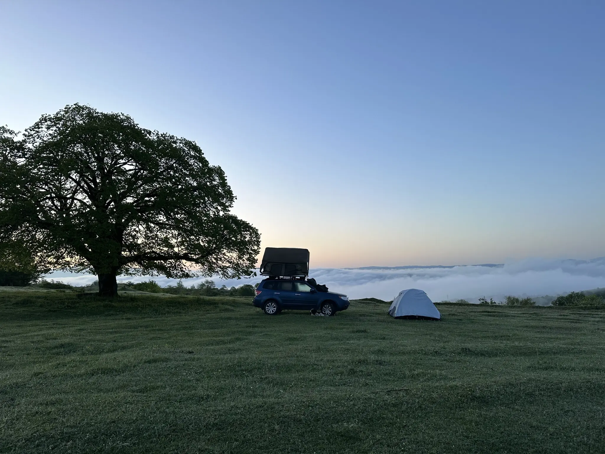 car with rooftop tent and ground tent camping above clouds