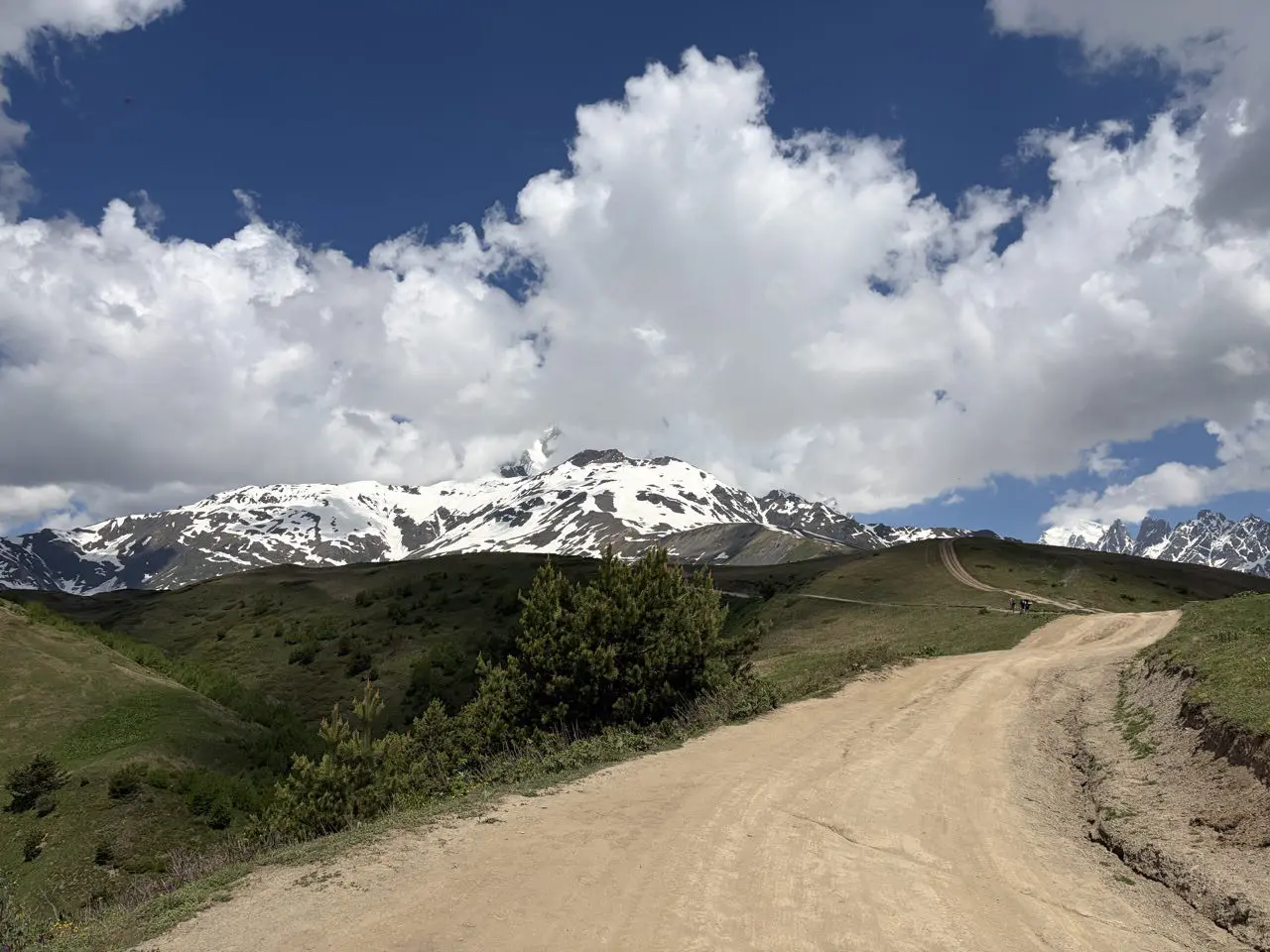 dirt road leading to snow-capped mountains under a cloudy sky