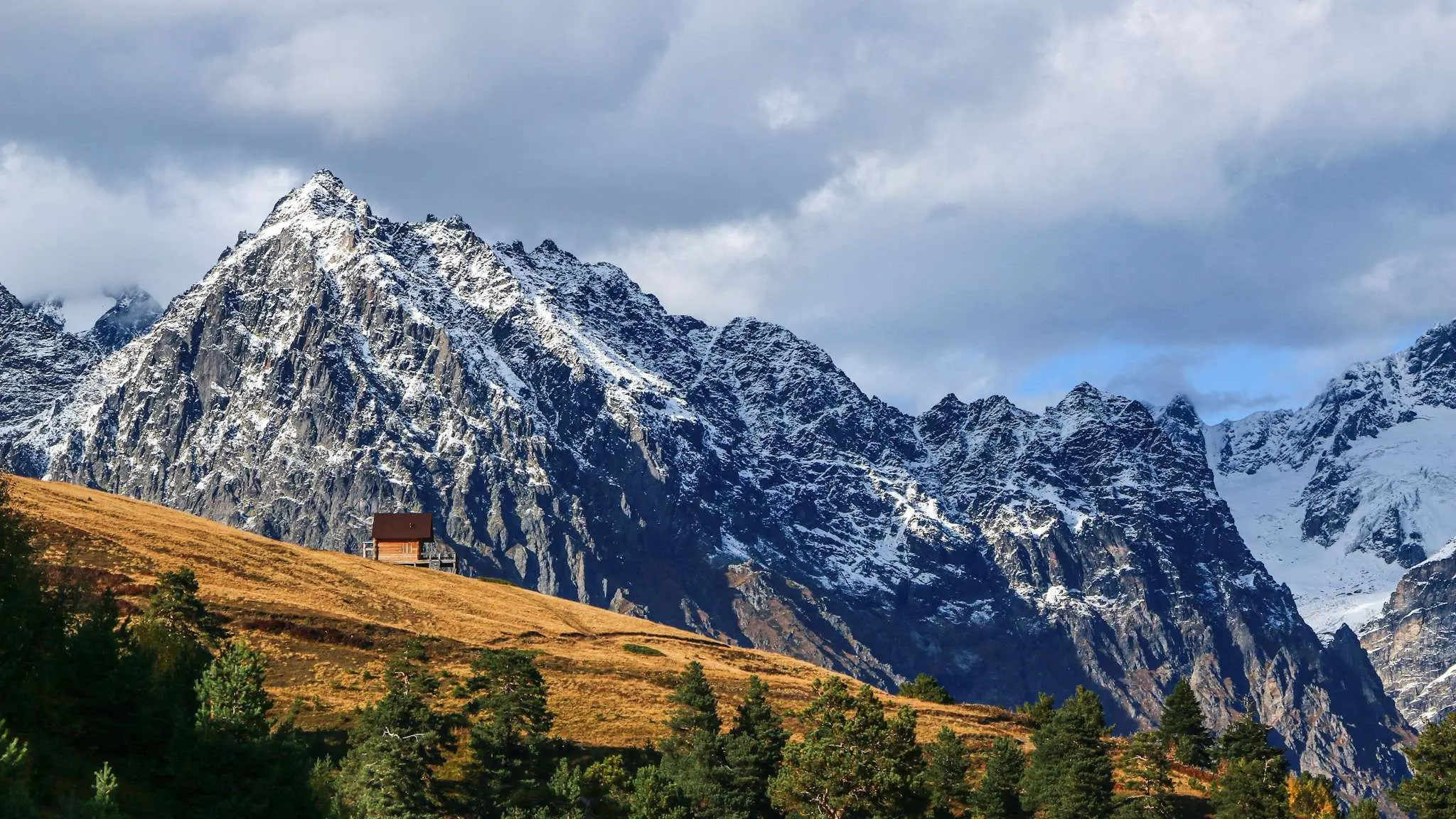wooden cabin on a golden hill with snowy mountains in Georgia