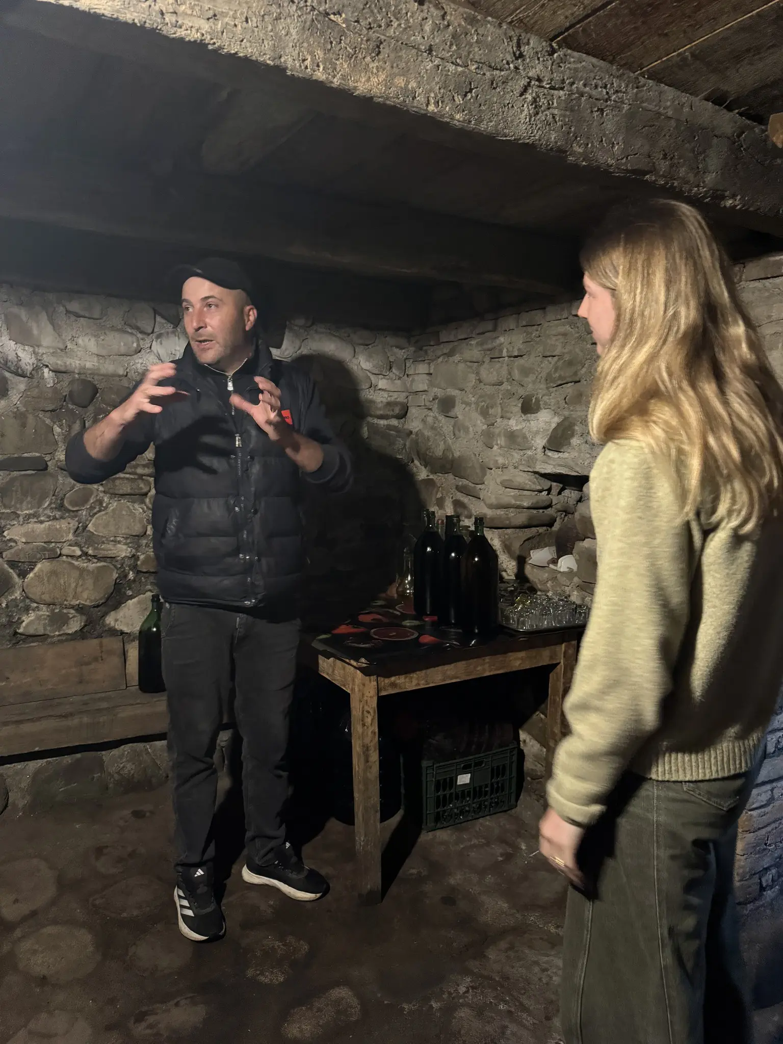 man talking to woman in a rustic wine cellar