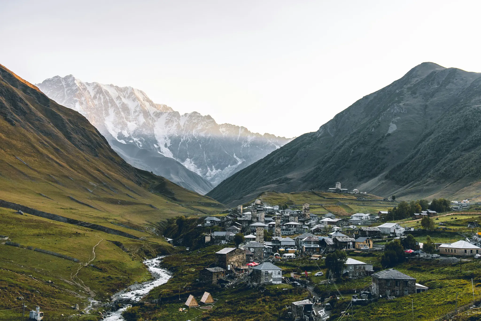 picturesque mountain village with a river and snowy peaks